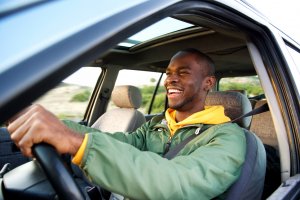 Man driving car, while wearing a hoddie and looking ahead.