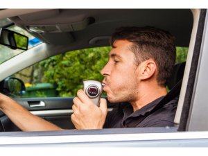Man taking breathalizer test while sitting on car.
