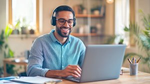 Man wearing headset and smiling while using his laptop.