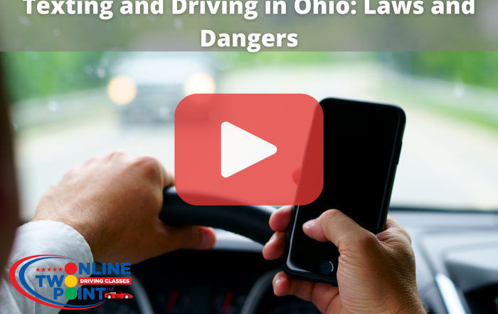 A person is holding a smartphone in their right hand while driving a car. The steering wheel is held in the left hand, and the individual appears to be focusing on the phone screen while driving.