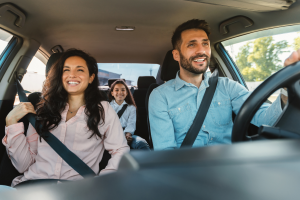 Family of four on car, smiling.