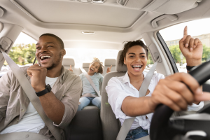 Family of three smiling whilr on car.
