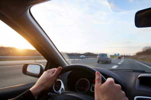 Close up of hands of person on car steering wheel.