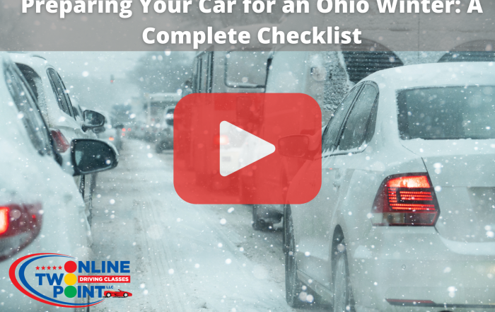 A street scene with several cars driving through heavy snowfall. The road and vehicles are covered in snow, and visibility is reduced.