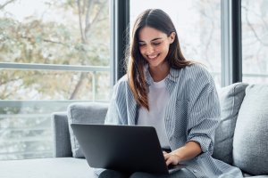 Concentrated girl sitting on couch working on laptop