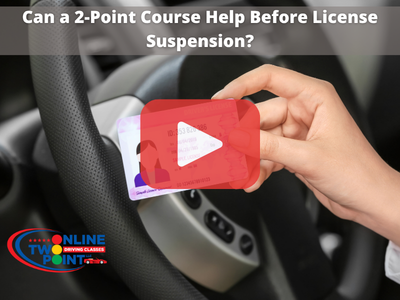 Person holding drivers licence infront of steering wheel. Red play buttom overlay and words: Can a 2-Point Course Help Before License Suspension?